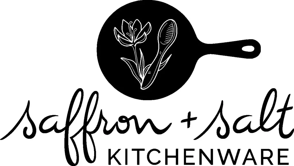 Logo of the kitchenware store named Saffron+Salt. The logo itself is a black skillet with white inset of a spoon of salt and a saffron flower.