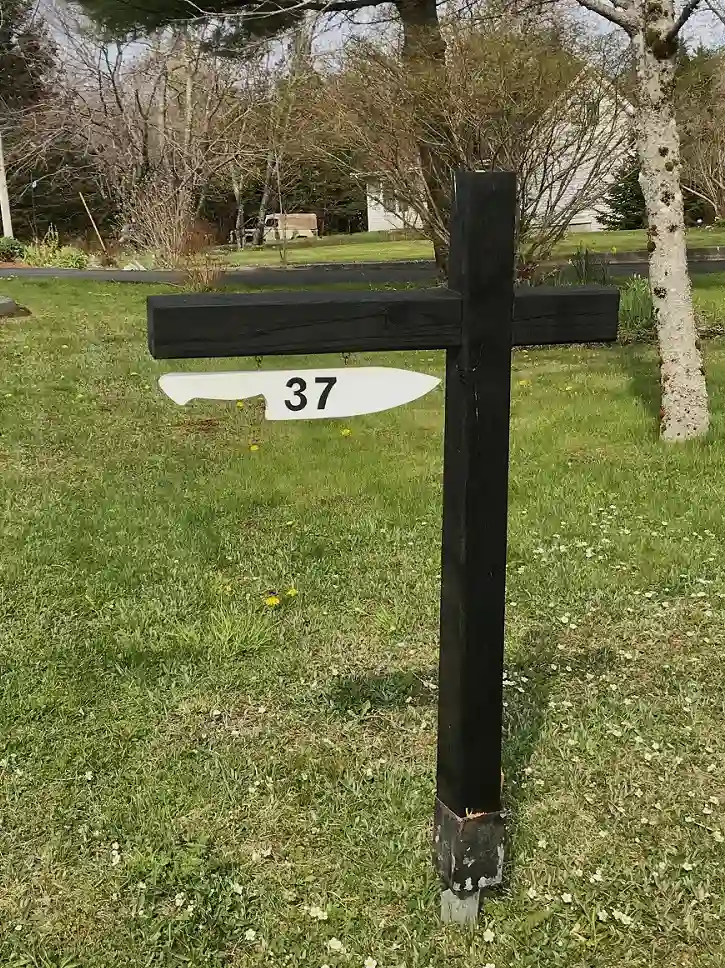 A black wooden street sign post with a white knife shaped plate hanging underneath with the number 37 on it.